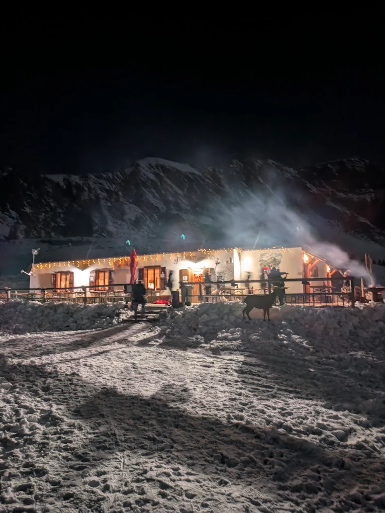 La baita illuminata di notte sulla neve, con le luci e il cervo sul piazzale